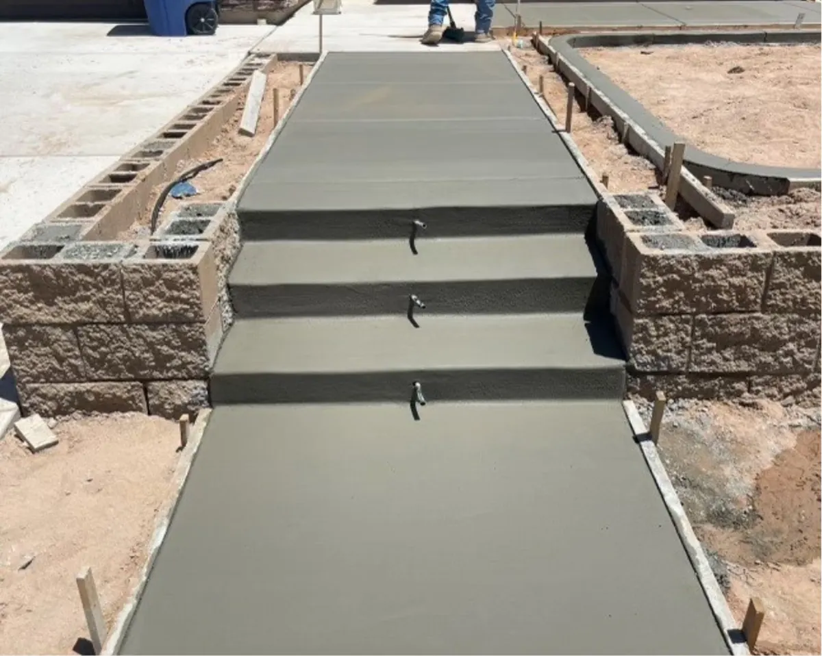 A walkway with three formed concrete steps between split-face block walls