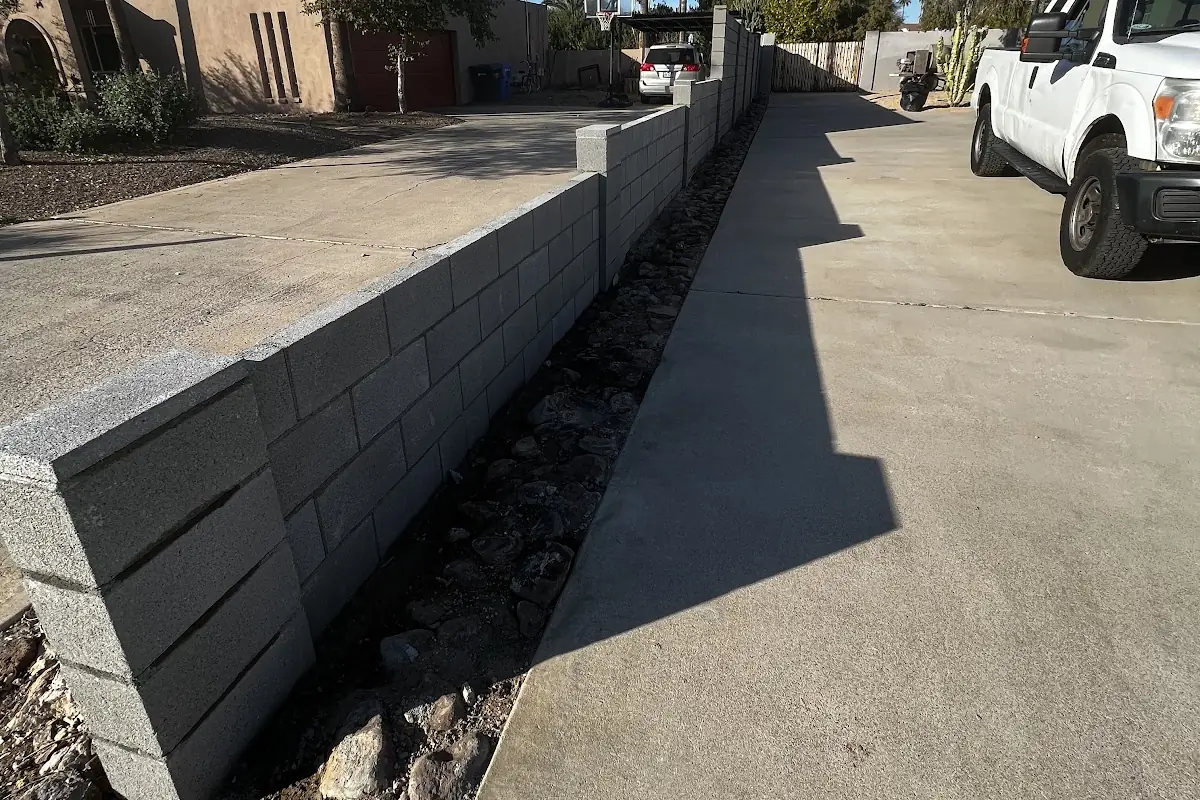 A new concrete strip poured beside a driveway and block wall
