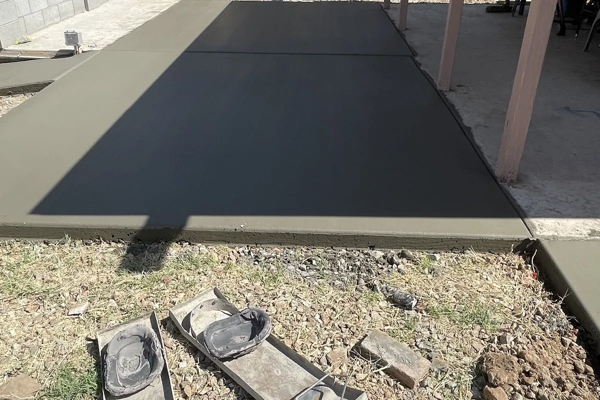 A freshly poured concrete slab beside a patio cover with forms still in place