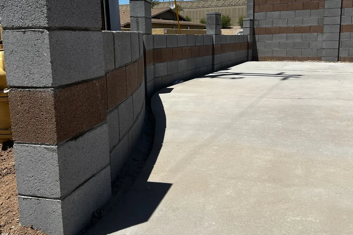 A new concrete parking pad beside block pillars and a block wall