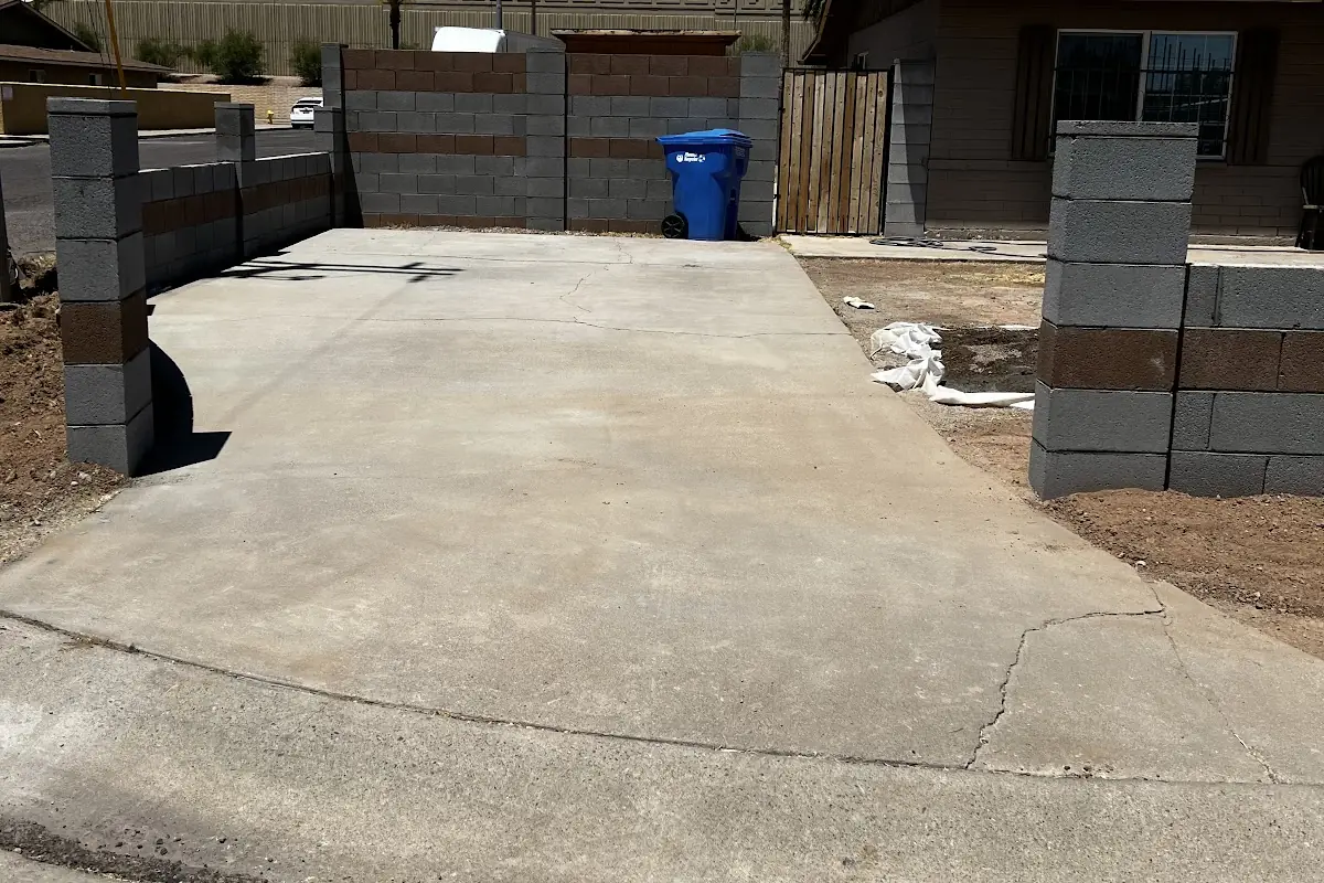 A new concrete parking pad between block walls and pillars, poured by our featured contractor