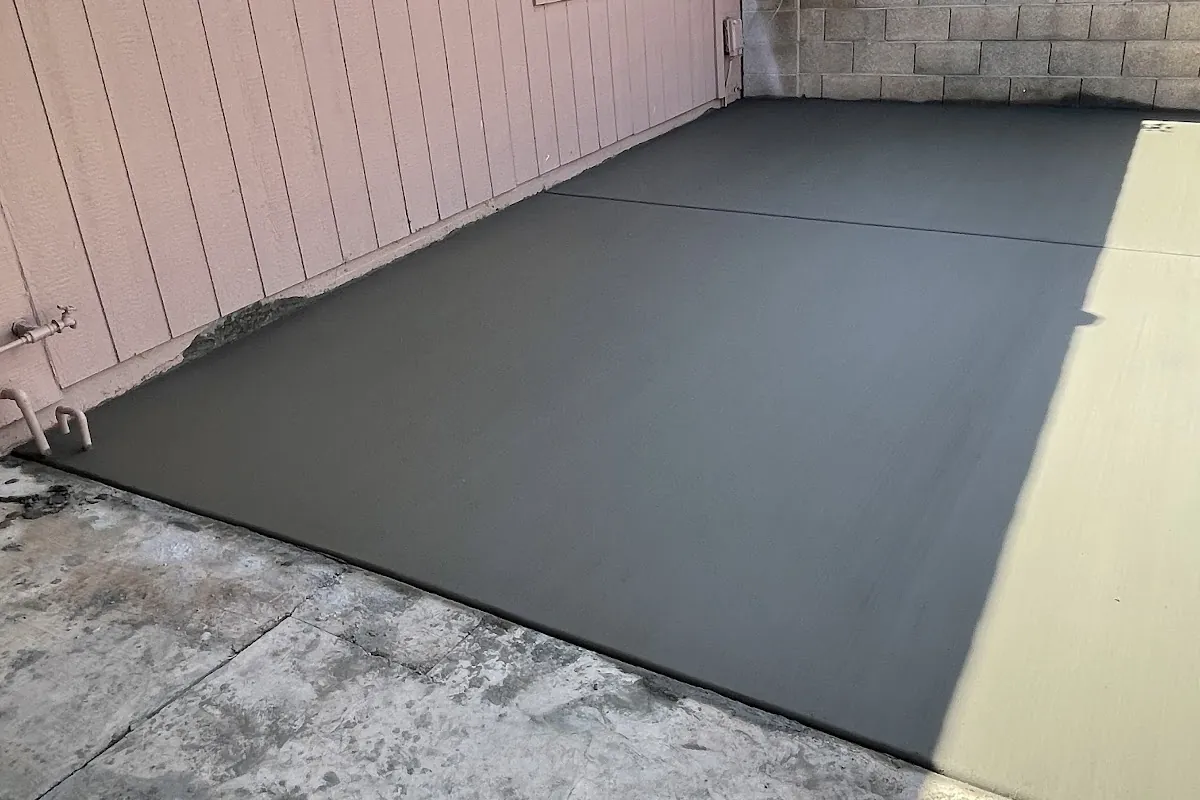 A freshly poured concrete patio slab against a house and block wall