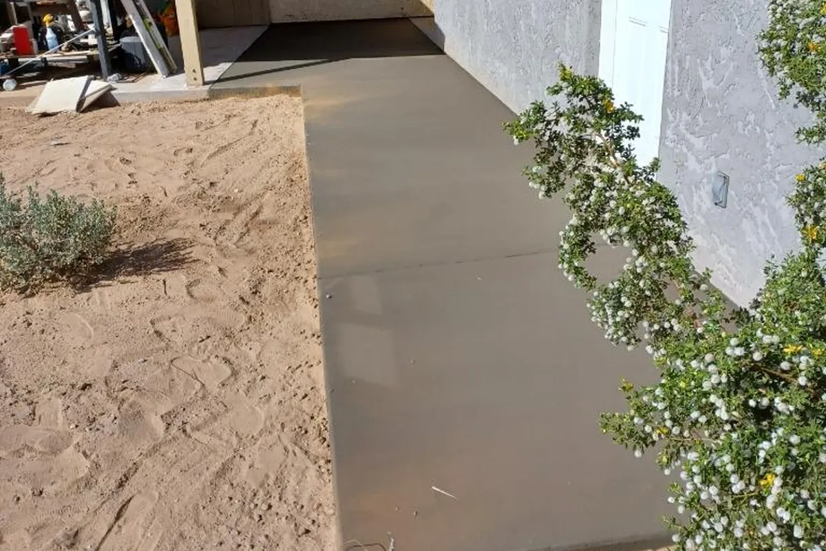 A new concrete strip poured along the side of a house, the kind of side-yard spot where equipment pads go
