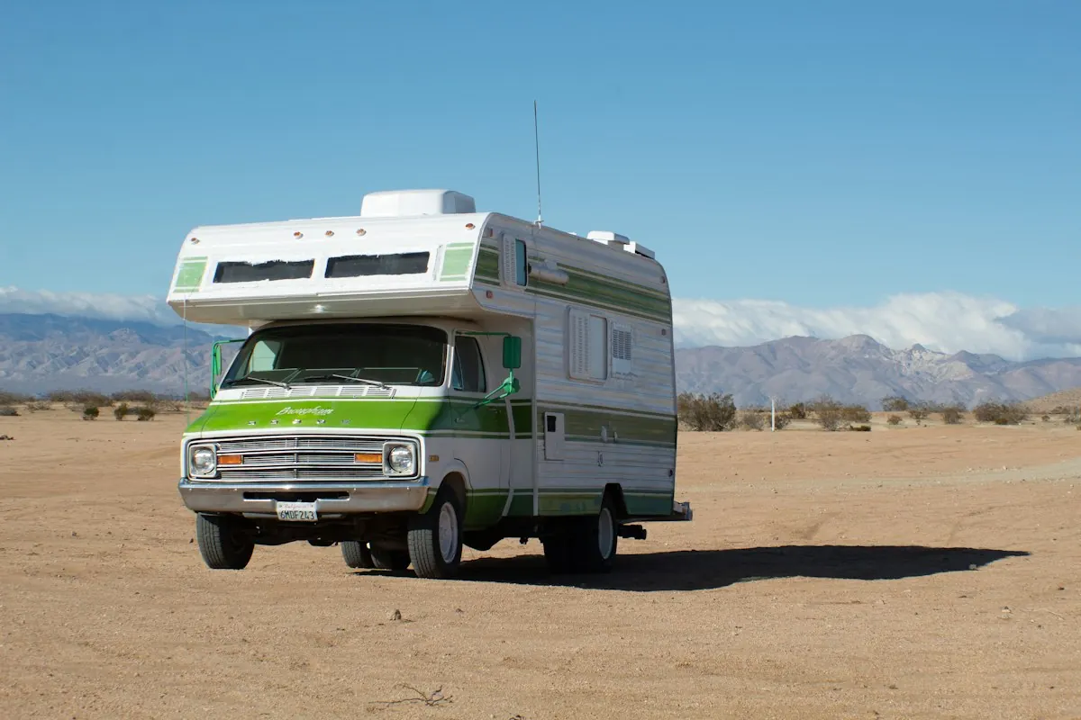 A vintage motorhome parked on bare desert dirt under a clear Arizona sky