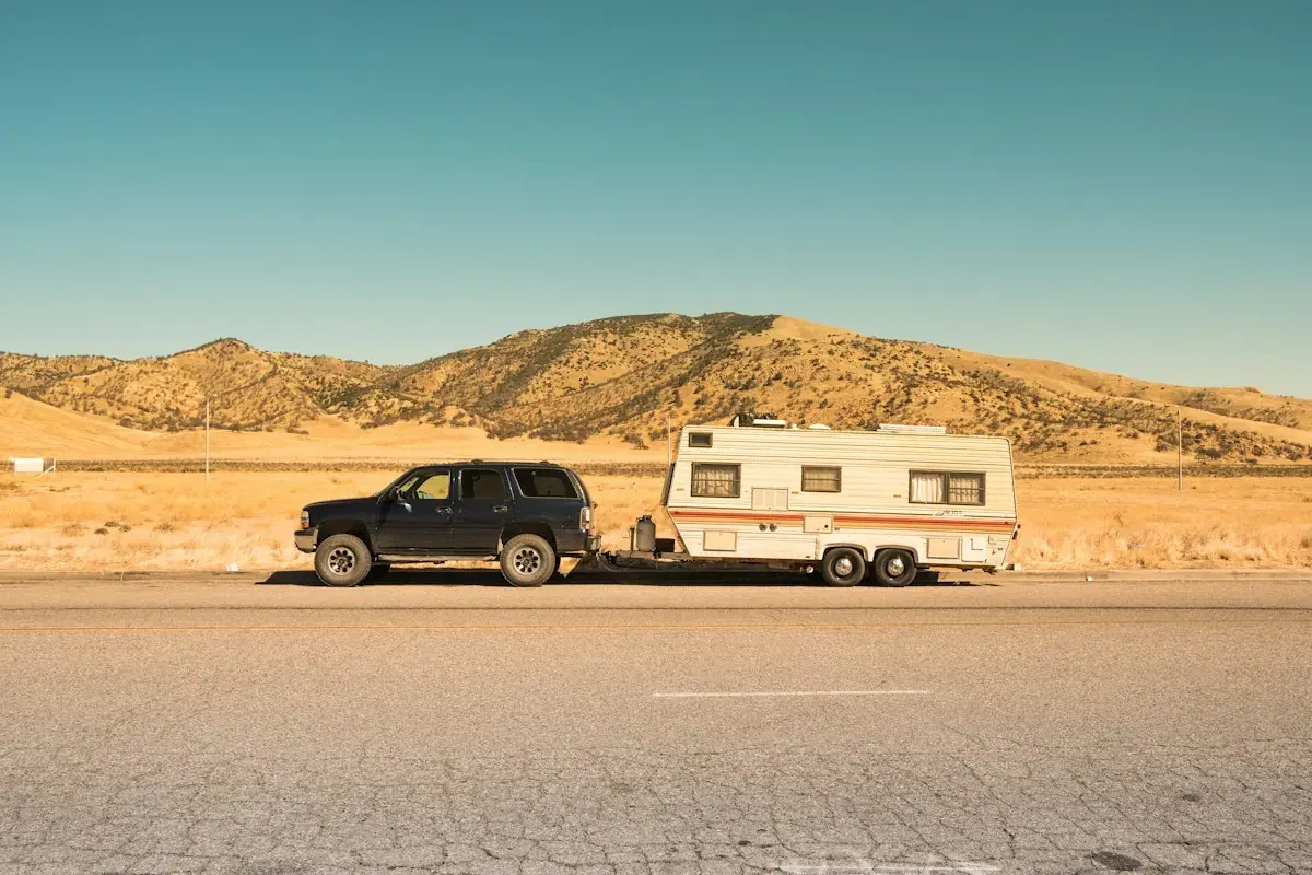 An SUV towing a travel trailer on a desert road